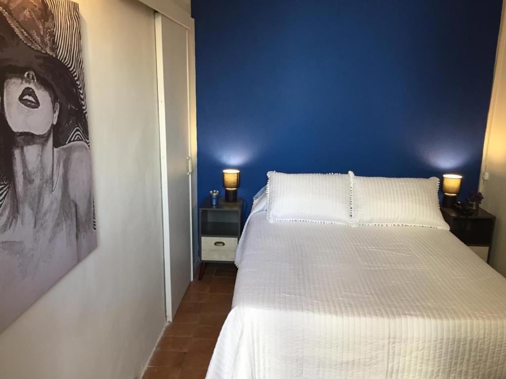 um quarto com uma cama branca e uma parede azul em HOTEL COMERCIO PLAYA em Montevidéu