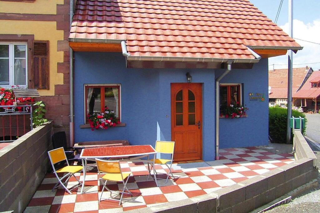 una casa azul con una mesa y sillas en un patio en Semi-detached house, Hinsbourg, en Hinsbourg