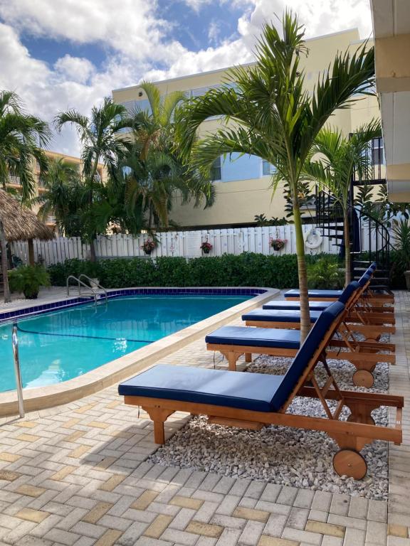 a group of lounge chairs next to a swimming pool at Beach Aqualina Apartments in Fort Lauderdale