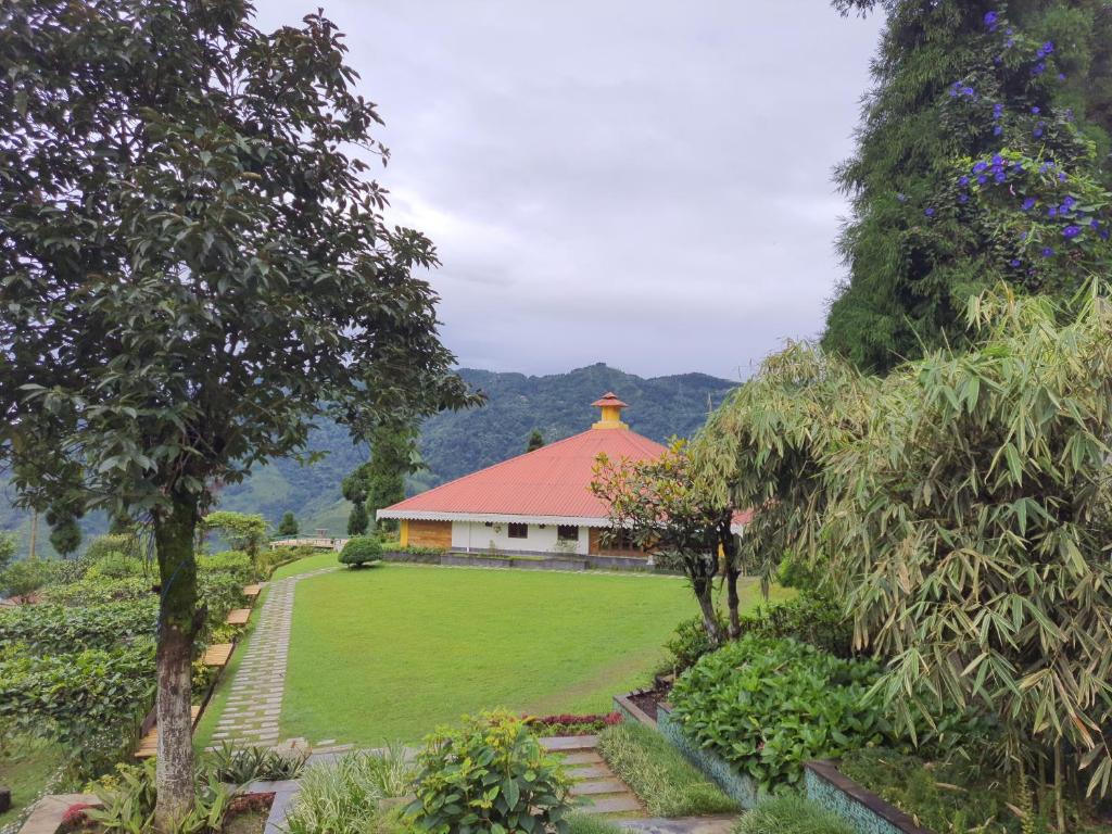 a building with a red roof in a garden at Chamong Chiabari Mountain Retreat in Darjeeling