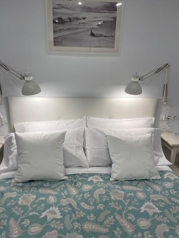 - un lit avec des oreillers blancs et une photo sur le mur dans l'établissement Nuestro Rinconcito del Soho, à Malaga