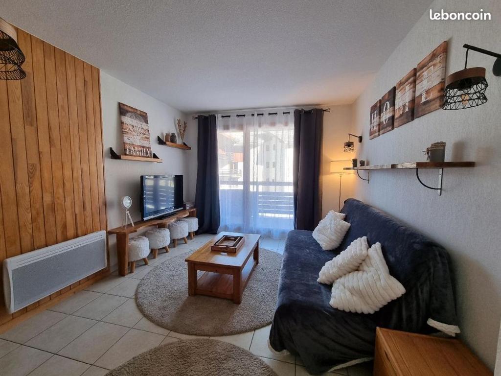 Una sala de estar con un sofá azul y una mesa. en Appartement T2-5 couchages L'écrin des Orres 1800, en Les Orres
