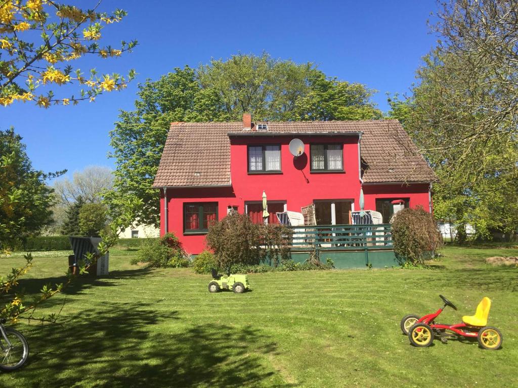 una casa roja con un patio con juguetes delante en Gutspark Schwarbe mit Reiterhof - Ferienhaus 3 en Mattchow
