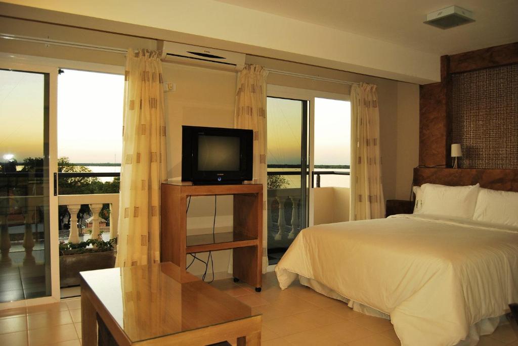 um quarto com uma cama, uma televisão e uma varanda em La Rozada Suites em Corrientes