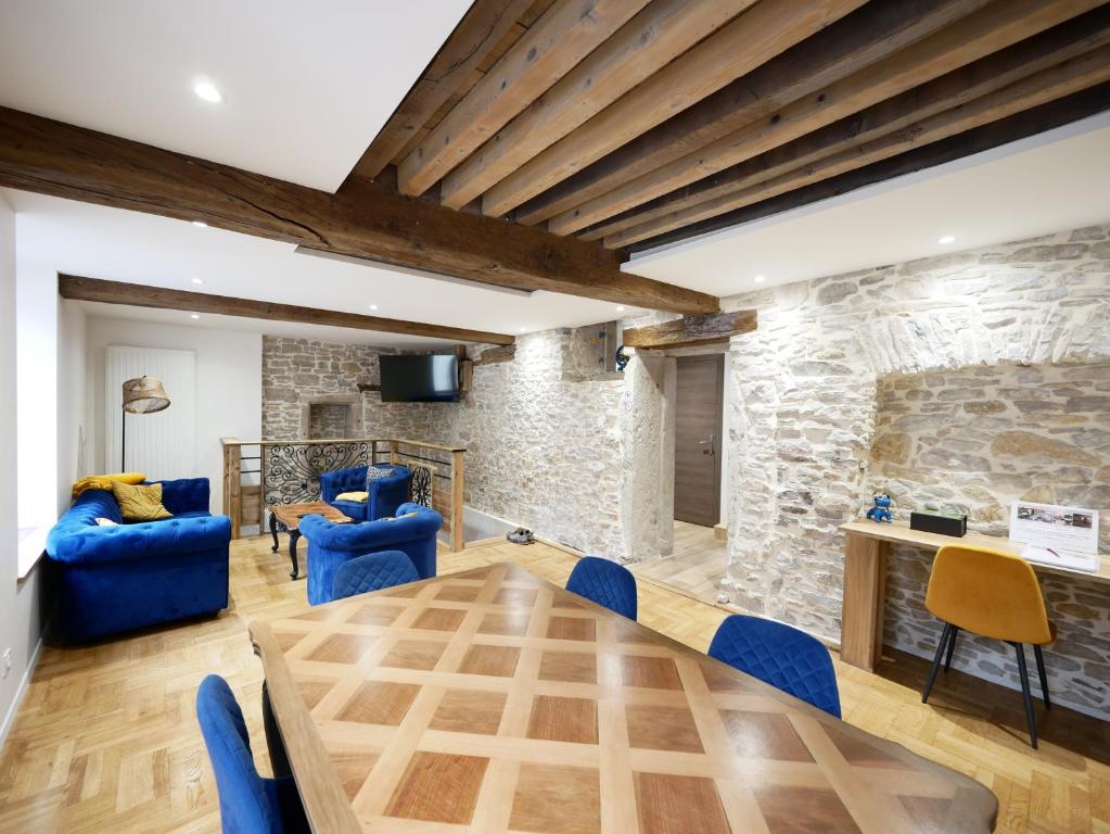 a dining room with blue chairs and a stone wall at Gîte de Crémieu - gitesdesbalcons-com in Crémieu
