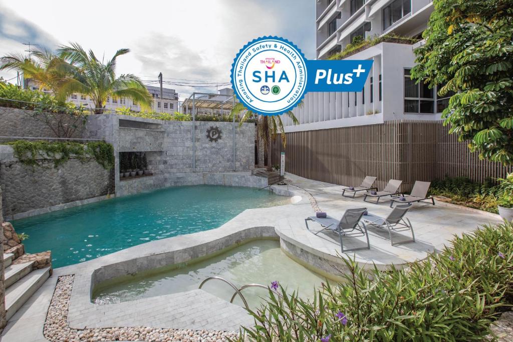 a swimming pool with chairs and a sign that reads shka plus at Pearl Hotel - SHA Plus in Phuket