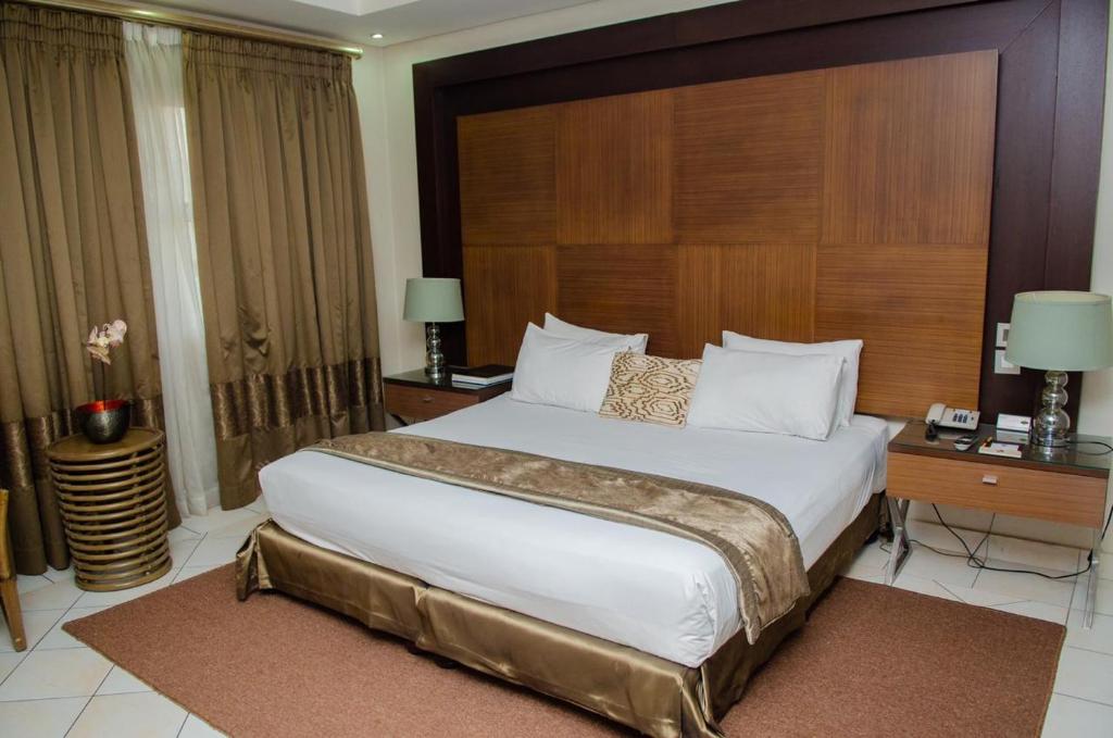 een slaapkamer met een groot bed met een houten hoofdeinde bij Hotel 2001 in Maputo