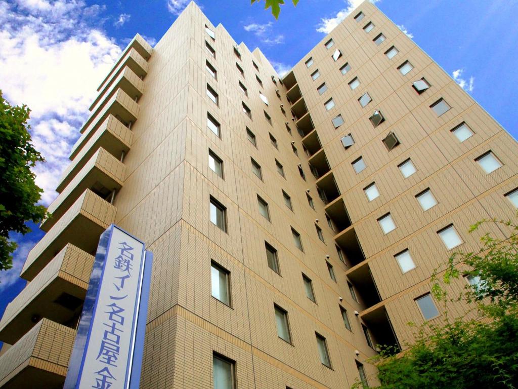 wysoki budynek z znakiem przed nim w obiekcie Meitetsu Inn Nagoya Kanayama w mieście Nagoja