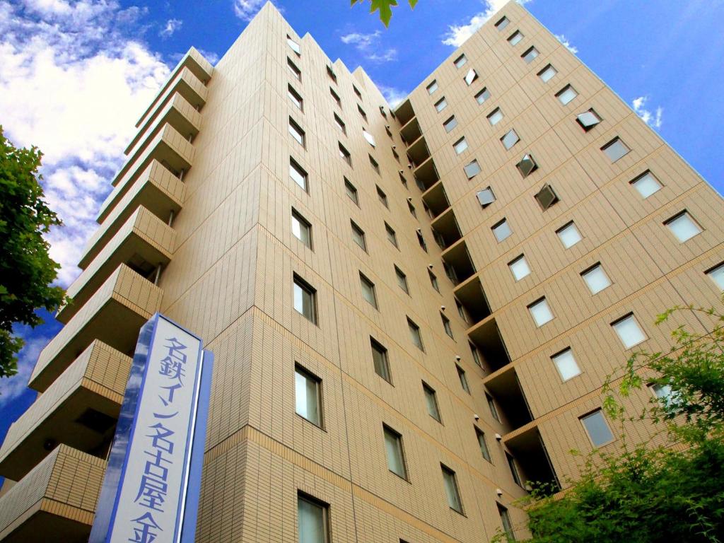 a tall building with a sign in front of it at Meitetsu Inn Nagoya Kanayama in Nagoya