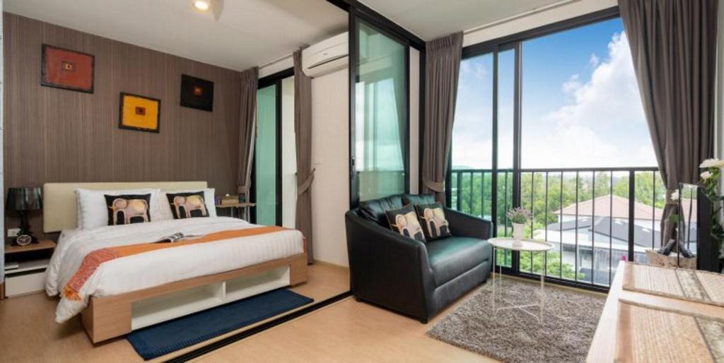 1 dormitorio con 1 cama, 1 silla y balcón en Zcape2 Condominium, en Thalang