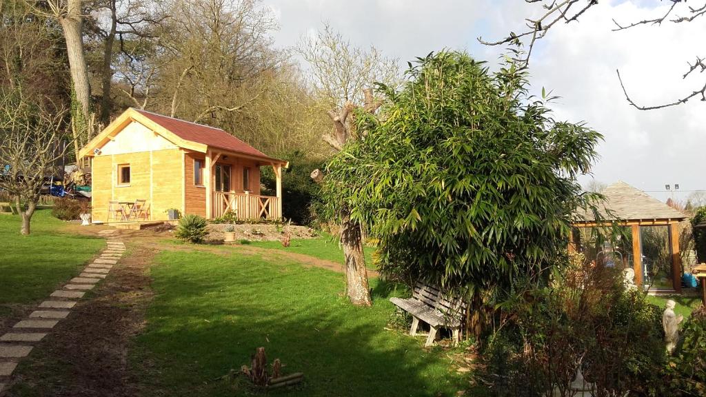een klein huis in een tuin met een bankje bij au calme dans Etretat in Étretat