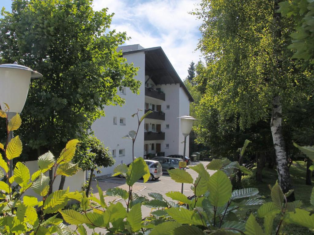 ein weißes Gebäude mit Autos auf einem Parkplatz in der Unterkunft Apartment Am Birkenhain-8 by Interhome in Seefeld in Tirol