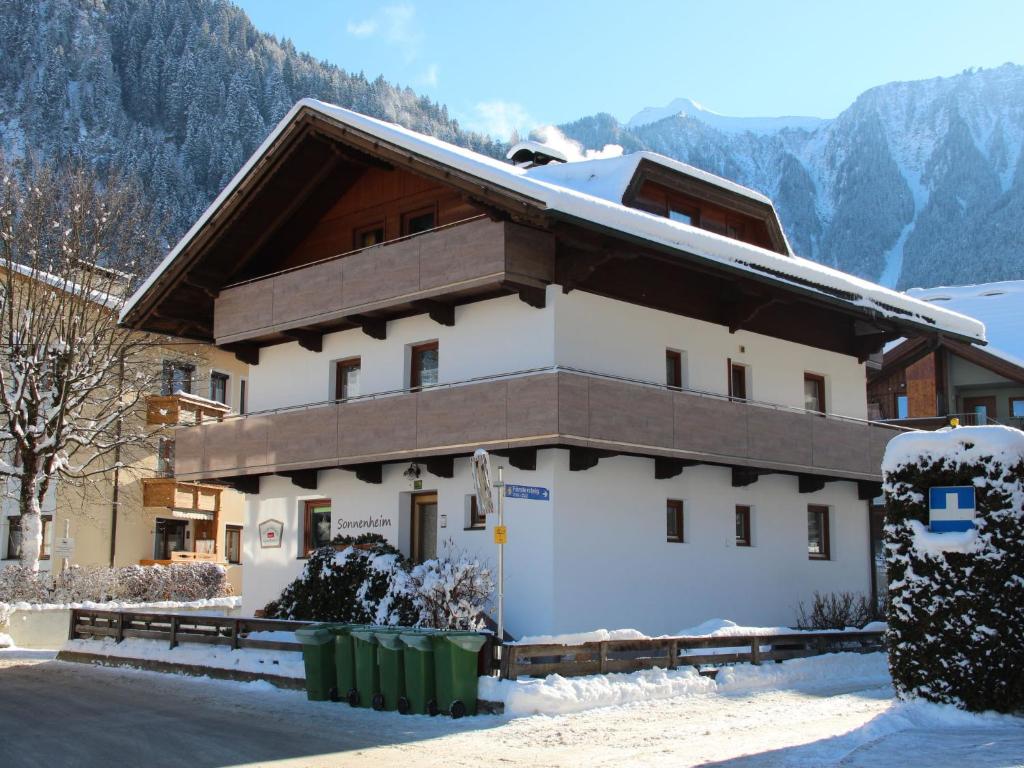 a building in the snow with a mountain in the background at Apartment Sonnenheim-1 by Interhome in Mayrhofen