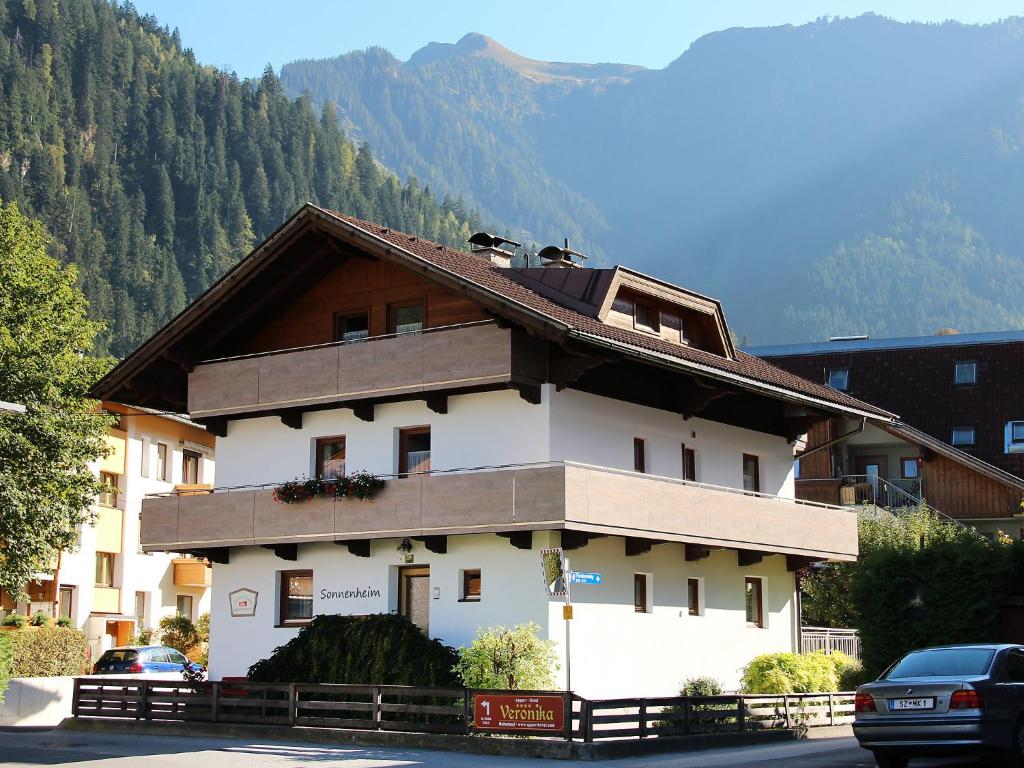 ein weißes Gebäude mit einem Dach mit Bergen im Hintergrund in der Unterkunft Apartment Sonnenheim-2 by Interhome in Mayrhofen