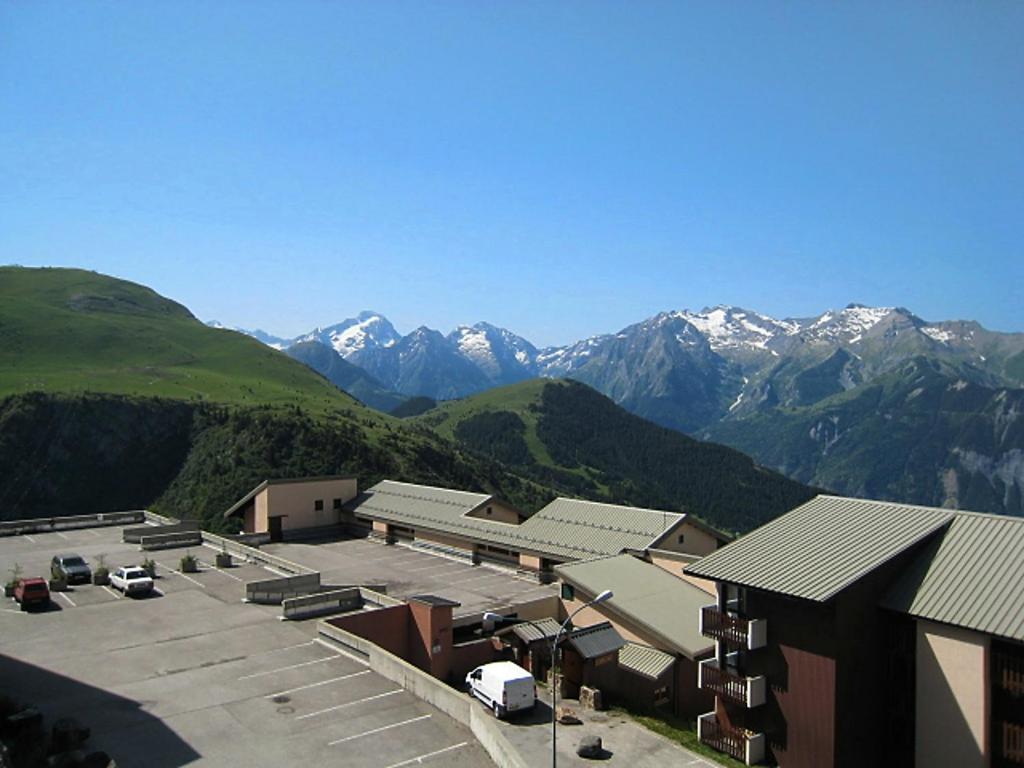 a view of a building with mountains in the background at Apartment Val d'Huez by Interhome in L'Alpe-d'Huez