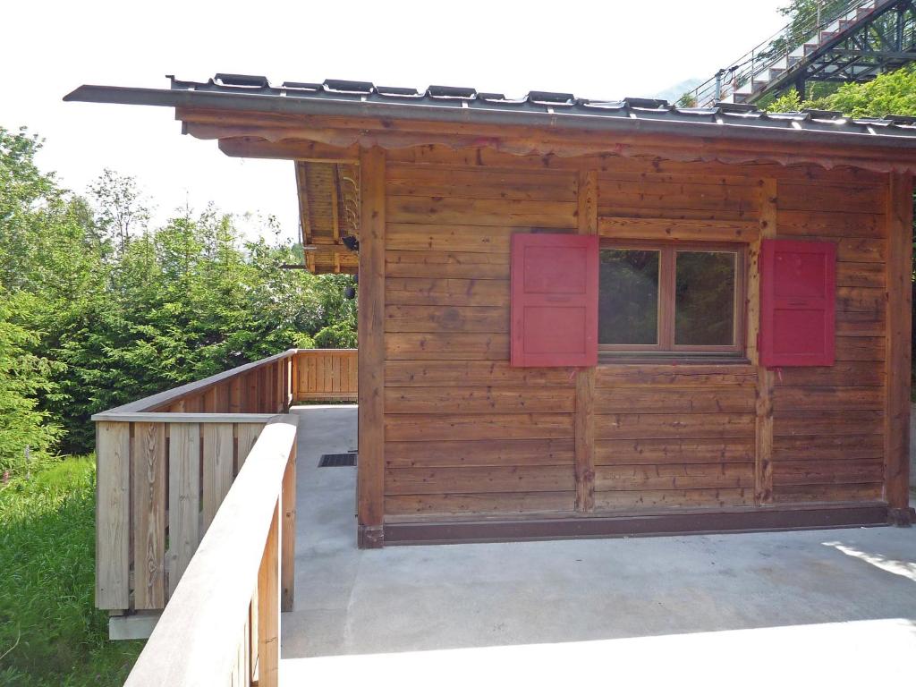 a wooden cabin with red shutters on a deck at Chalet Evasion by Interhome in Les Bossons