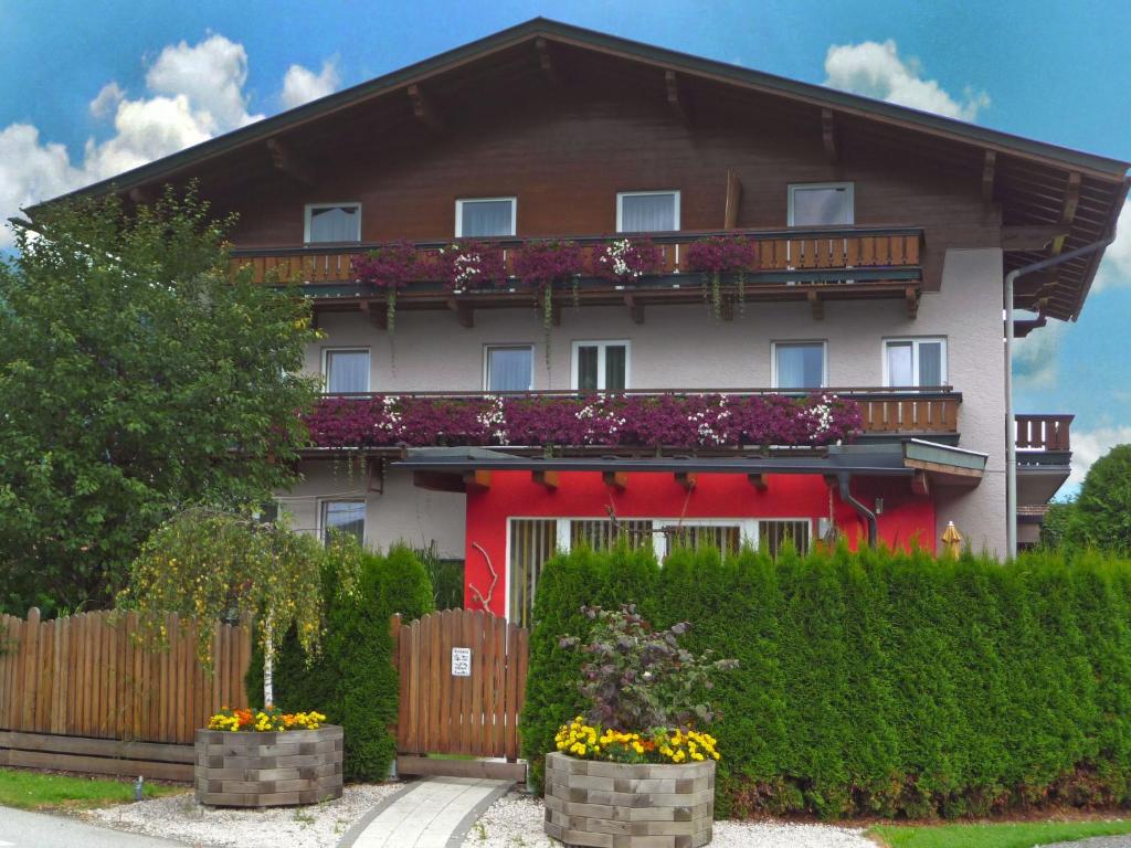 ein rotes und weißes Haus mit einem Zaun und Blumen in der Unterkunft Apartment Rupertus-3 by Interhome in Maishofen