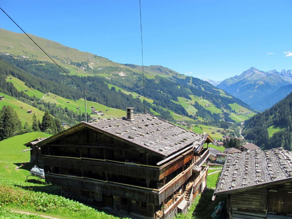 un groupe de bâtiments sur une colline avec des montagnes en arrière-plan dans l'établissement Chalet Lippnerhütte - LNH120 by Interhome, à Tux