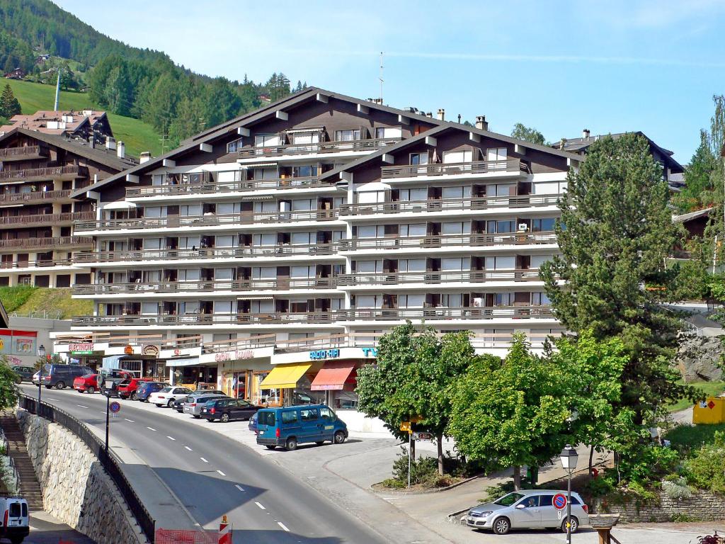 ein großes Gebäude mit Autos vor einer Straße in der Unterkunft Apartment Valaisia 35A by Interhome in Nendaz