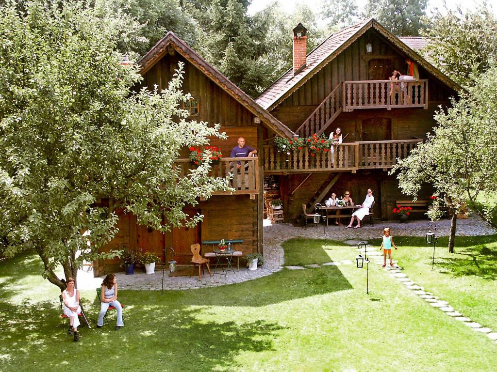 a large wooden house with people sitting on the deck at Chalet Troadkasten by Interhome in Neuhofen im Innkreis