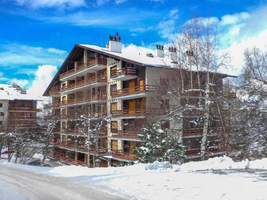 un grand bâtiment dans la neige avec une route devant dans l'établissement Apartment Derborence 25 by Interhome, à Nendaz
