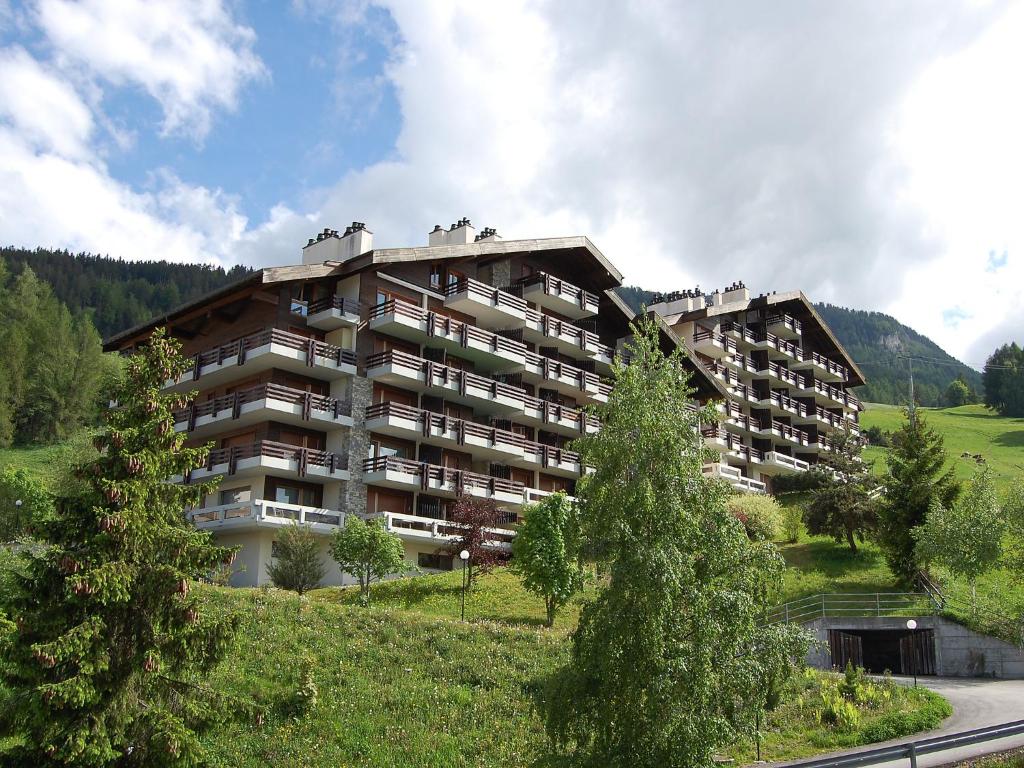 un grand immeuble situé sur une colline arborée dans l'établissement Apartment Hauts De Nendaz B OP by Interhome, à Nendaz