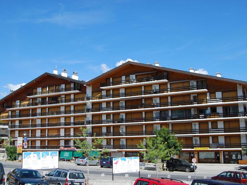a large building with cars parked in a parking lot at Apartment Christiania 2 O3 by Interhome in Nendaz