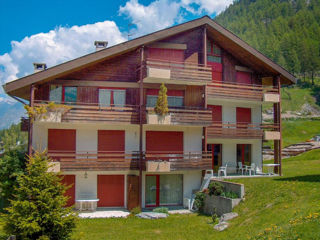 ein großes Haus mit roten Türen auf einem Hügel in der Unterkunft Apartment Gamma by Interhome in Zermatt