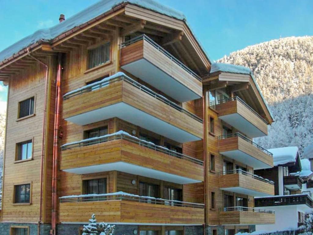 een houten gebouw met sneeuw bedekte bergen op de achtergrond bij Apartment Rütschi-3 by Interhome in Zermatt