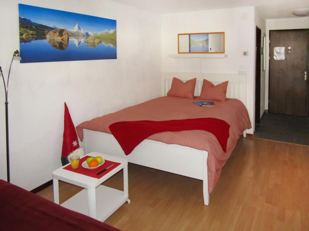 um quarto com uma cama e uma mesa com uma tigela de fruta em Apartment Sungold-1 by Interhome em Zermatt