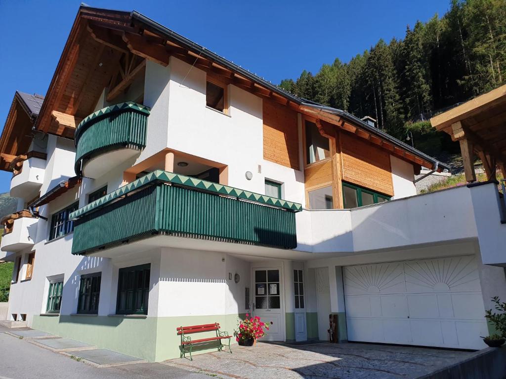 ein großes weißes Gebäude mit grünen Balkonen und einer Bank in der Unterkunft Apartment Kathrein - ISL505 by Interhome in Ischgl