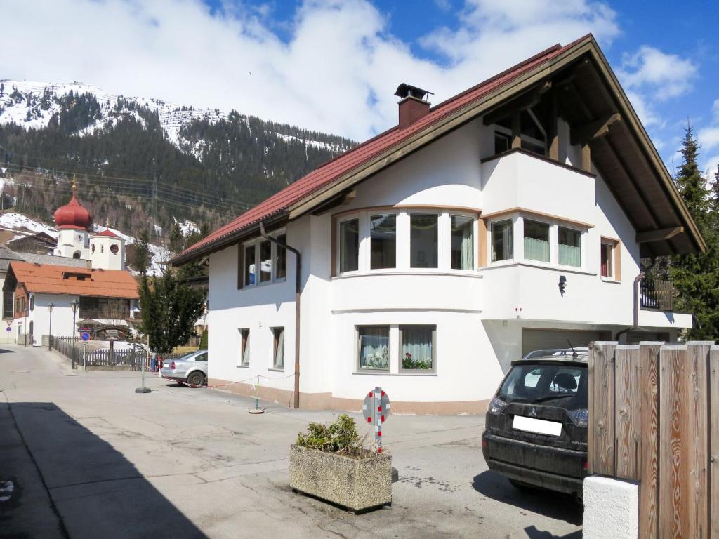 une maison blanche avec une voiture garée devant elle dans l'établissement Apartment Schmiedbach - STA255 by Interhome, à Sankt Anton am Arlberg