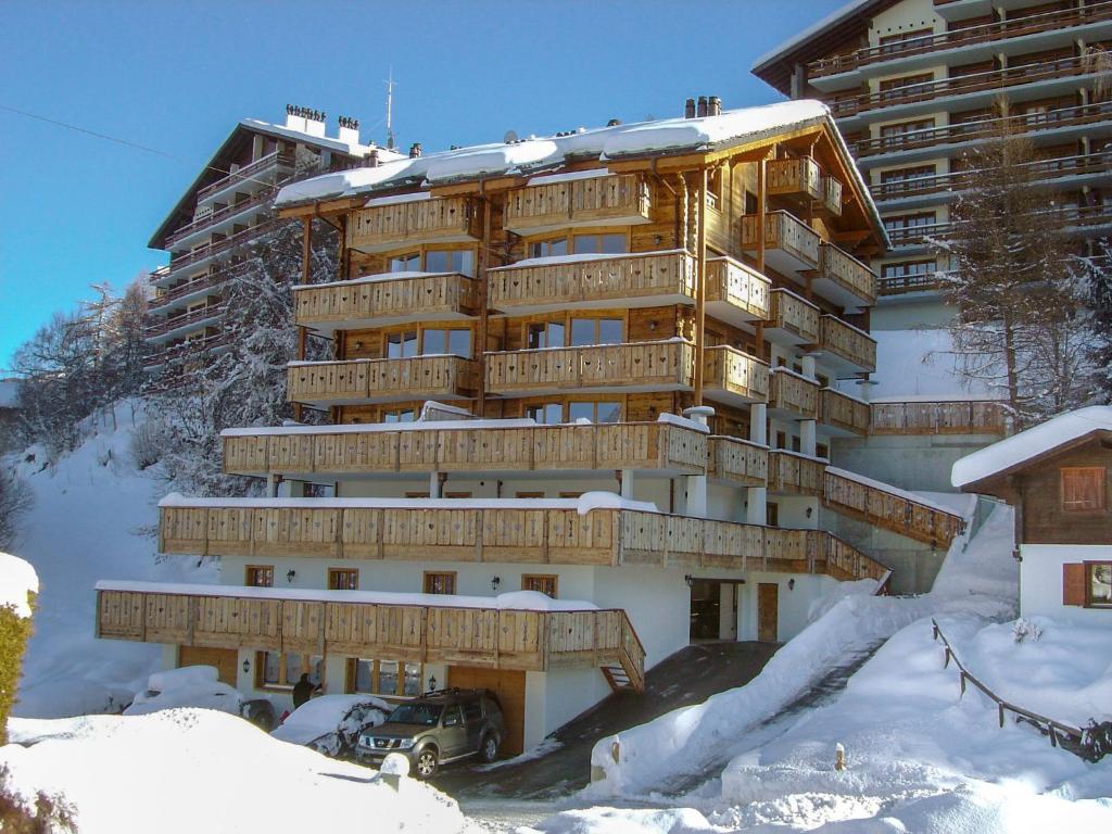 a large building in the snow with a car in front at Apartment Les Terrasses du Paradis 5a by Interhome in Nendaz