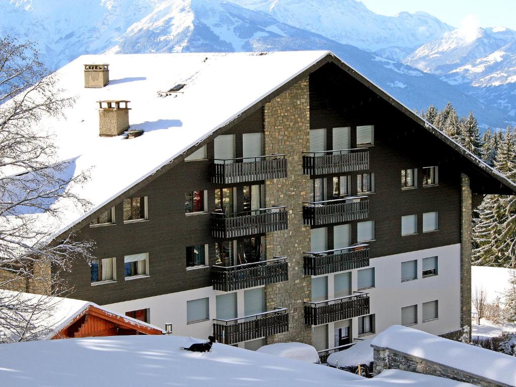 a building with snow on the roof with mountains in the background at Apartment Marignac 33 by Interhome in Villars-sur-Ollon