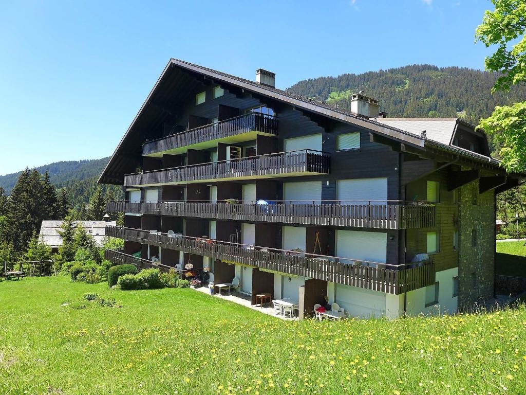 ein großes Gebäude auf einem Hügel mit einem grünen Feld in der Unterkunft Apartment Marignac 33 by Interhome in Villars-sur-Ollon