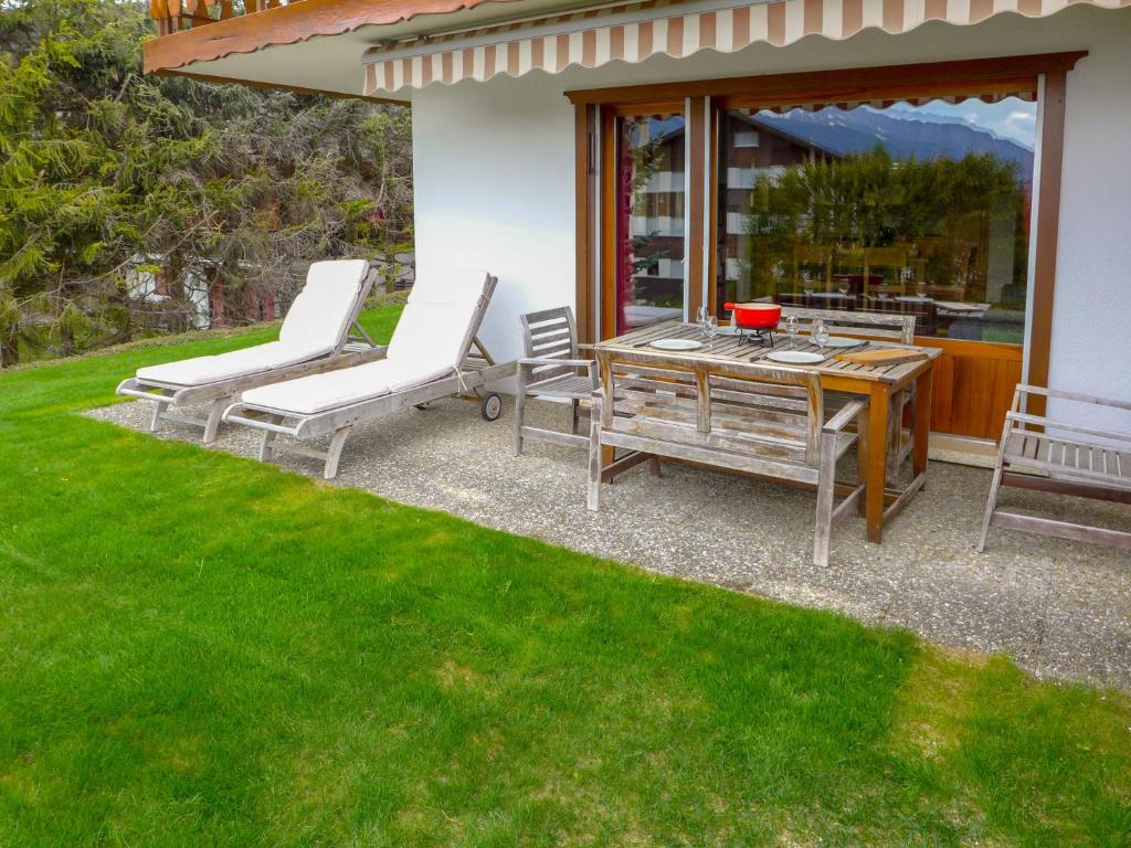 eine Terrasse mit einem Tisch und Stühlen auf einem Rasen in der Unterkunft Apartment La Joie by Interhome in Crans-Montana