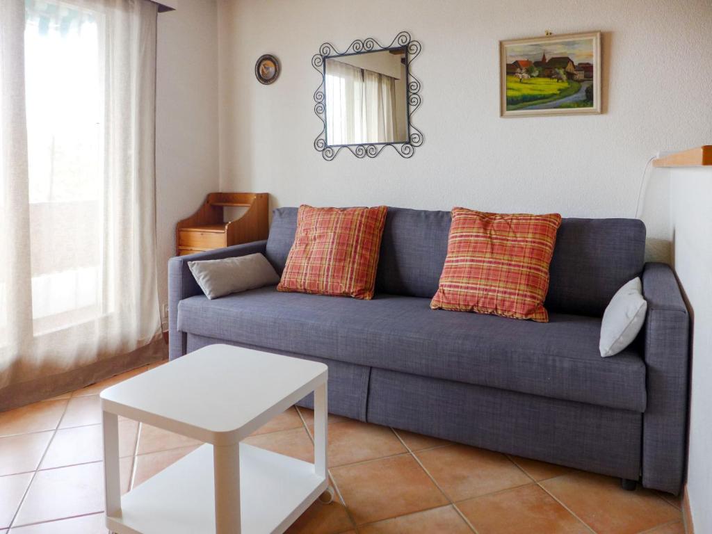 a living room with a blue couch and a table at Apartment Les Girolles B14 by Interhome in Villars-sur-Ollon