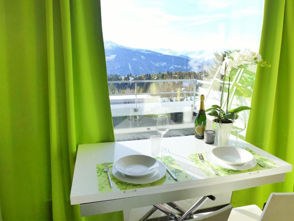 a white table with a green curtain and a window at Apartment Jeanne D'Arc Apt- C-28 by Interhome in Crans-Montana