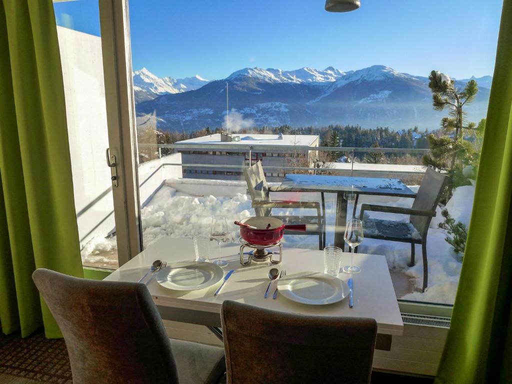a table and chairs with a view of the mountains at Apartment Jeanne D'Arc Apt- C-28 by Interhome in Crans-Montana