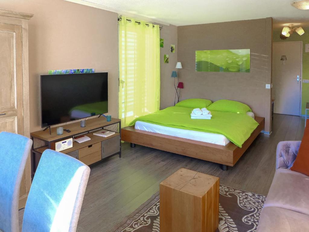 a bedroom with a green bed and a flat screen tv at Apartment Jeanne D'Arc Apt- C-28 by Interhome in Crans-Montana