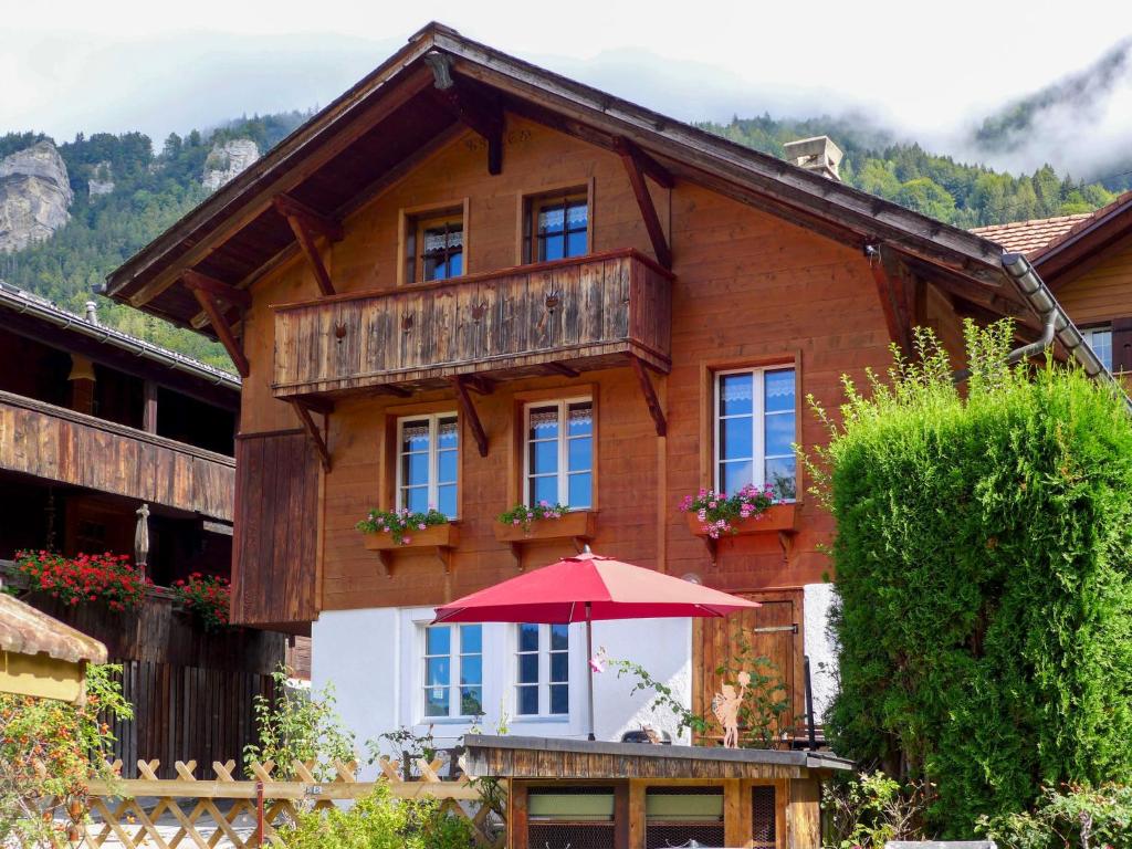 ein Haus mit einem roten Regenschirm davor in der Unterkunft Chalet Hüsli by Interhome in Brienzwiler