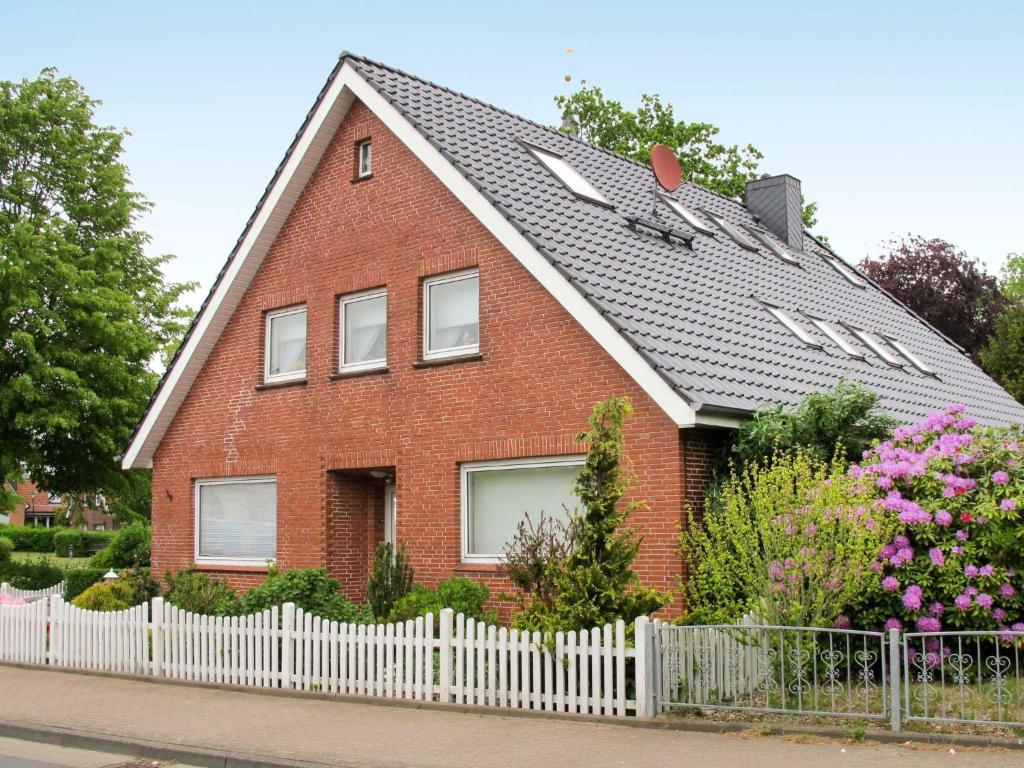a red brick house with a white fence at Apartment Söhle by Interhome in Neuenkirchen
