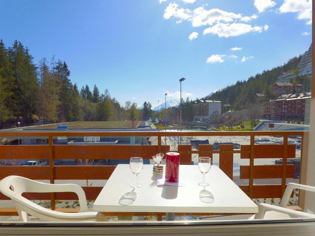 una mesa blanca con 2 copas de vino en el balcón en Apartment Le Farinet-2 by Interhome, en Crans-Montana