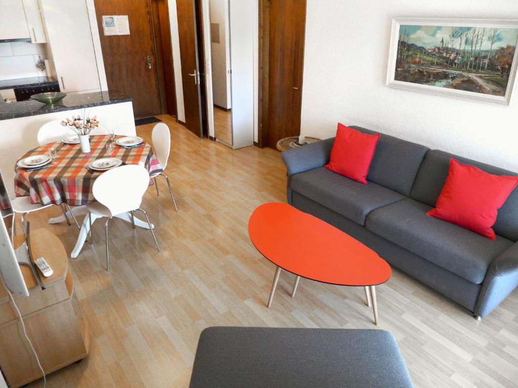 a living room with a couch and a table with red pillows at Apartment Victoria A-B-C-2 by Interhome in Crans-Montana