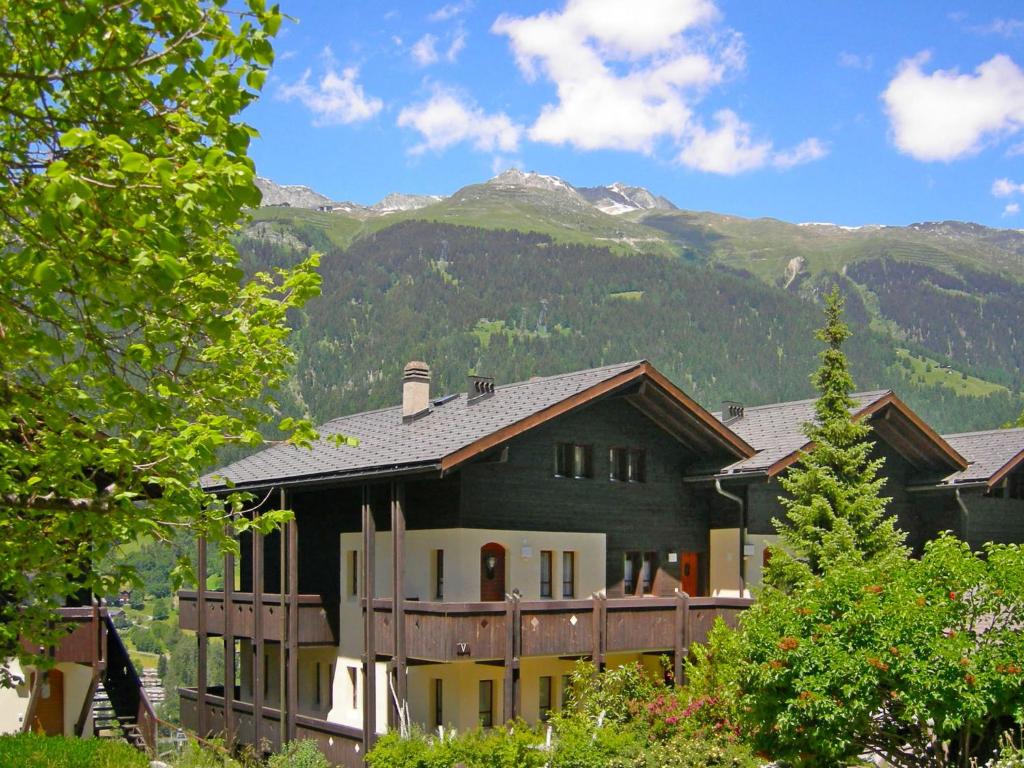 une grande maison avec des montagnes en arrière-plan dans l'établissement Apartment Aragon N103 by Interhome, à Fiesch