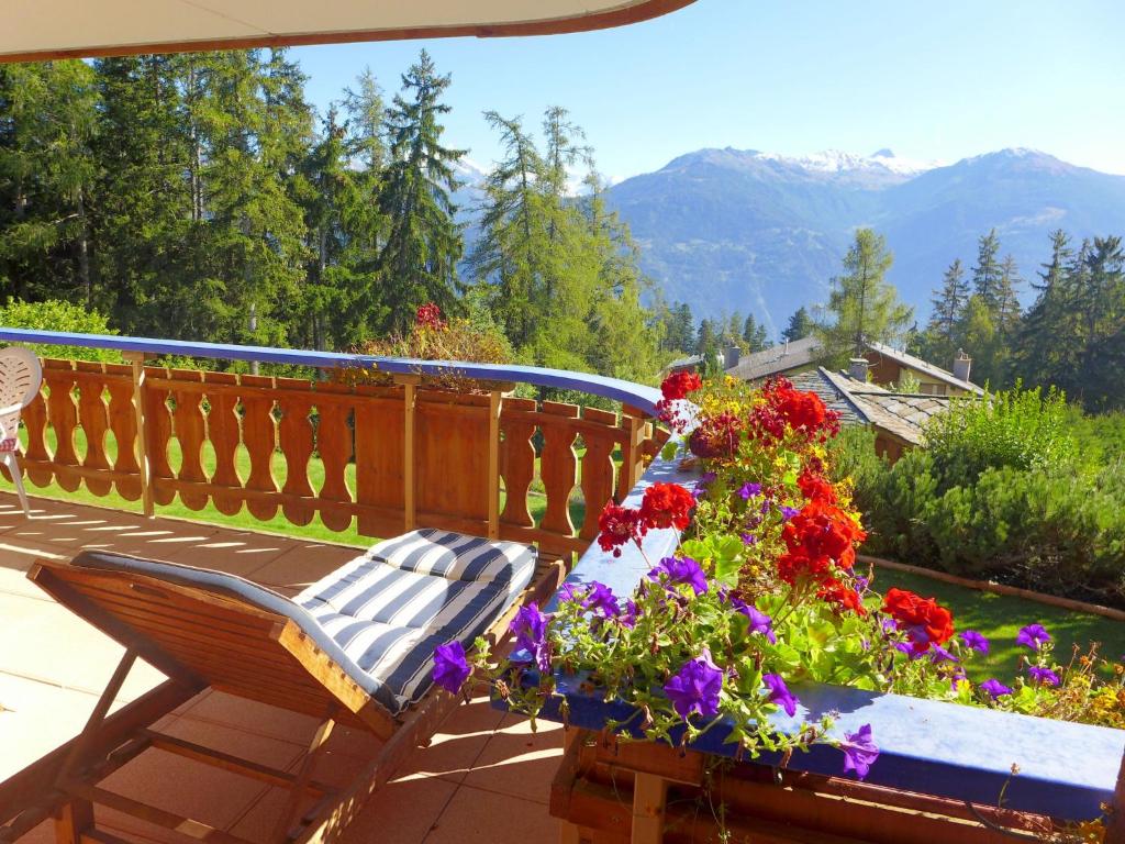 un banco sentado en un balcón con flores en Apartment Le Chalet by Interhome en Crans-Montana