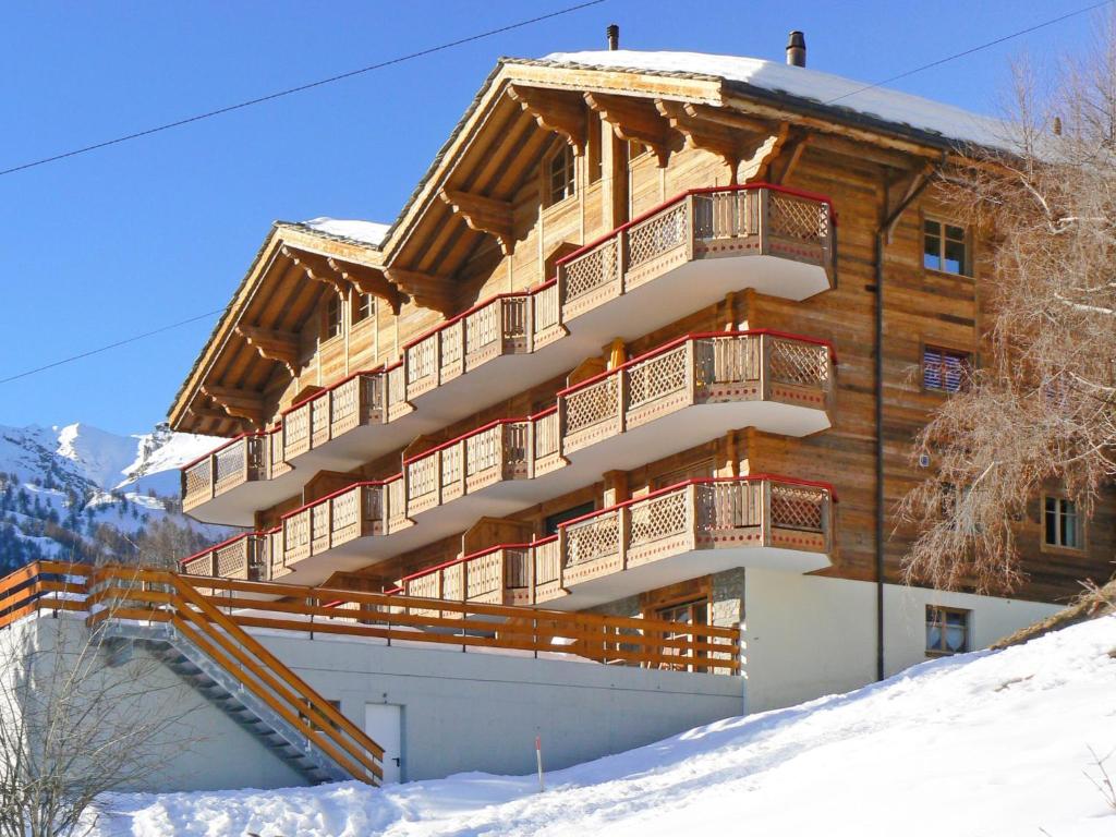een groot houten gebouw met een balkon in de sneeuw bij Apartment Ardève 7 by Interhome in Ovronnaz