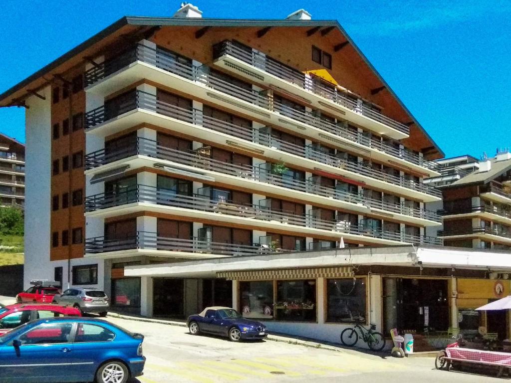 a large building with cars parked in front of it at Apartment Les Platanes I5 by Interhome in Nendaz