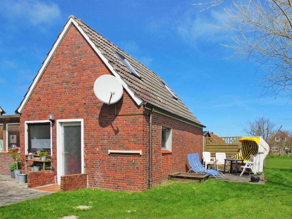 ein rotes Backsteinhaus mit 2 Stühlen und einem Tisch in der Unterkunft Holiday Home Osterkamp by Interhome in Friederikensiel