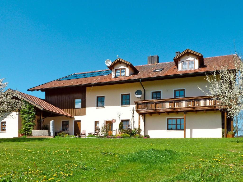 a large white house with a deck on a green field at Apartment Freisinger-1 by Interhome in Zachenberg